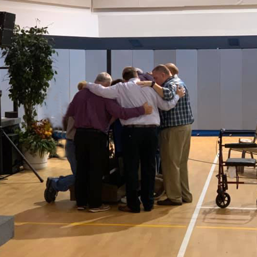 Men praying arm-in-arm