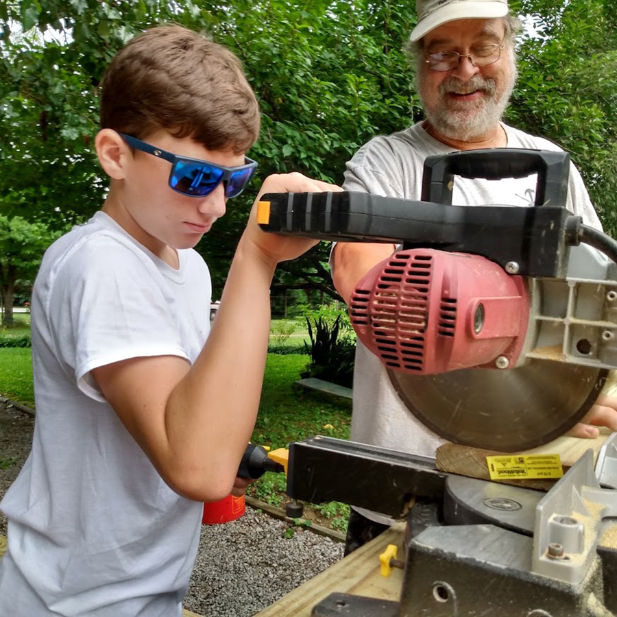 Student using saw while adult oversees