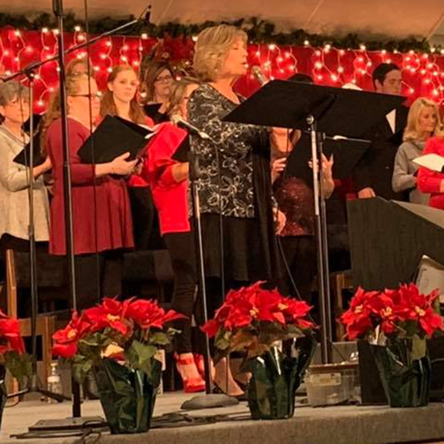 Woman singing behind row of poinsettias